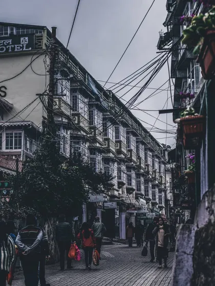 a narrow street in a hill station with a web of wires overhead. this image captures the organized chaos of urban life.