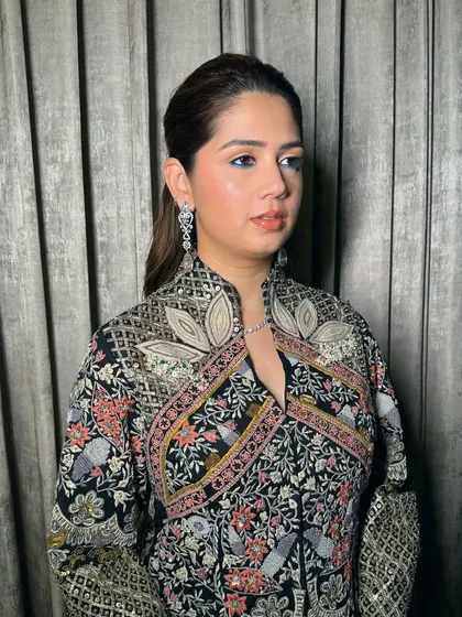 A chic and modern look for an evening event. The sleek ponytail and clean makeup are sophisticated, while the intricate black outfit adds a touch of drama.