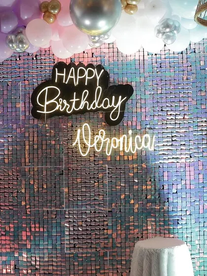 A vibrant and iridescent sequin wall serves as the backdrop for Veronica's 10th birthday. The custom neon sign and pastel balloon arch add a fun, youthful touch to the glamour.
