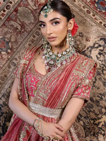 A regal bridal look featuring a rich pink lehenga and bronze smokey eyes. The makeup is bold yet balanced, perfect for a grand wedding.