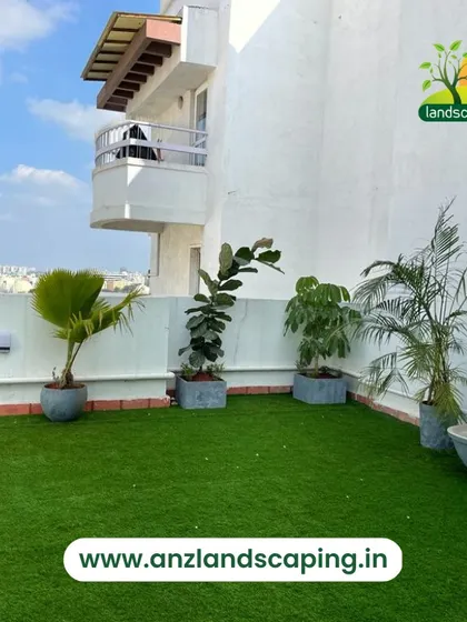 Another angle of a clean and green terrace design, showing how we use potted plants of varying heights to create depth and interest against a simple white wall.