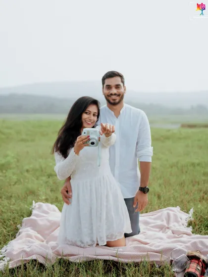 A fun and interactive shot from a picnic-themed session, where the bride-to-be playfully points her instant camera, capturing a memory within a memory.