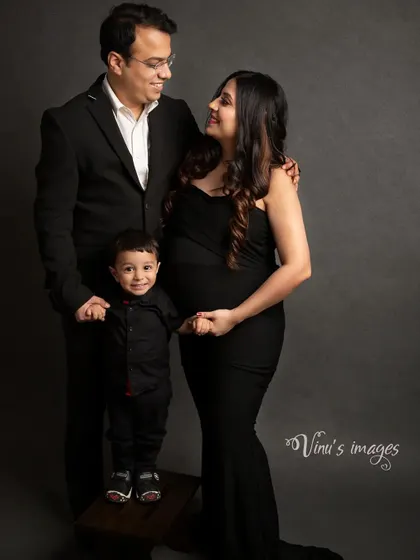 From three to four. This classic family maternity portrait in the studio captures the excitement of a growing family, with their young son standing proudly between his parents.
