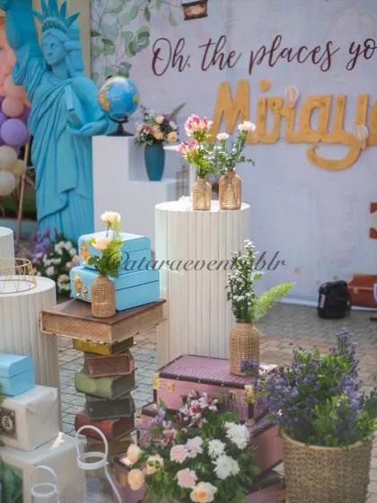 A detailed view of the travel-themed decor, with a miniature Statue of Liberty, stacked vintage books and suitcases, and lovely floral arrangements, all contributing to the "Oh, the places you'll go!" theme.