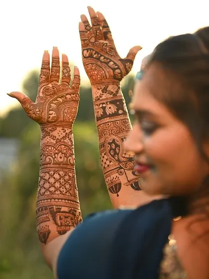 A beautiful candid shot of the bride, with her intricate mehendi visible as she looks away with a smile.