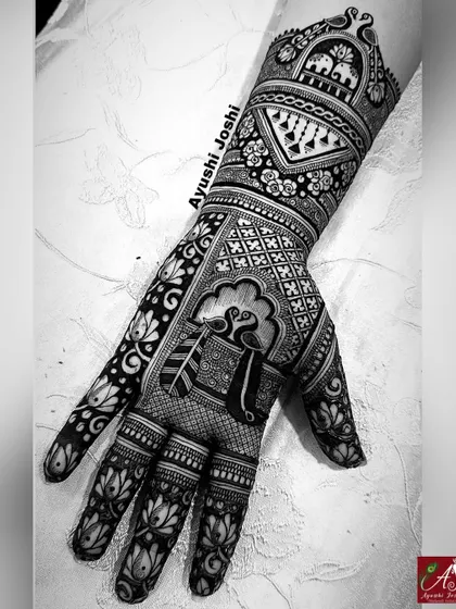 A black and white shot of an Indian designer mehendi, which emphasizes the contrast and clean lines of the peacock, lotus, and elephant patterns.