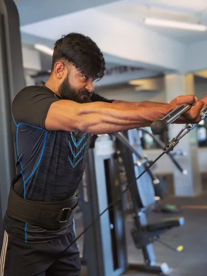 A cable fly variation that also engages the forearms and biceps, showing the intensity of a full upper body workout.