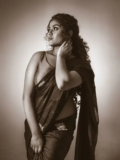 A different pose from the same traditional shoot. The monochrome look focuses attention on the elegant drape of the saree and the subject's expression.