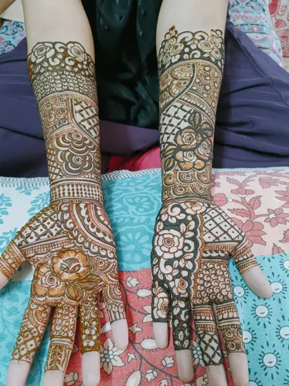 An example of how different patterns on each hand can still create a cohesive look. One hand features bold, dark floral work while the other uses finer lines, both connected by similar geometric elements.