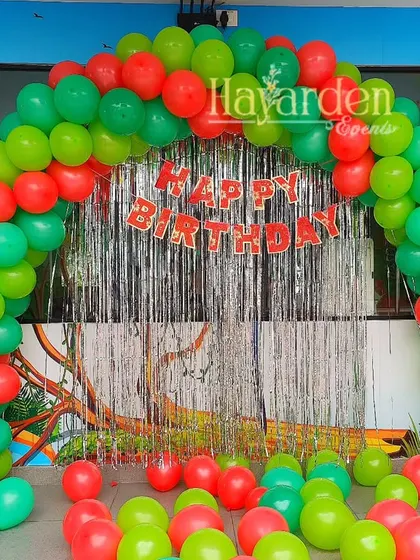 A classic balloon arch in red and green with a fringe backdrop. This is a simple, festive, and budget-friendly option for any celebration.