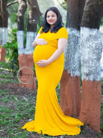 A radiant mom-to-be in a vibrant yellow gown. This classic solo maternity pose against the backdrop of painted trees is simple, elegant, and timeless.