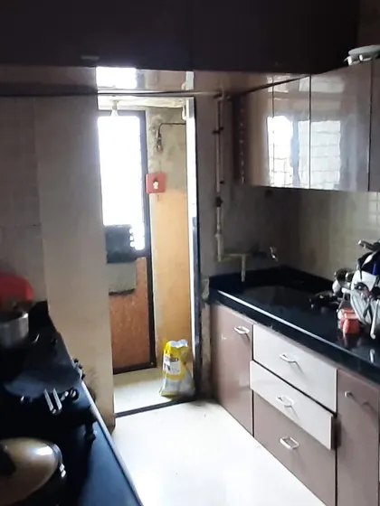 Our kitchen's earlier view shows the existing cabinets, dark countertop and busy work surface before the finished white-cabinet makeover.