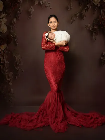 A stunning solo portrait of a mother in a red lace gown holding her newborn. This shot celebrates the mother and her special connection with her baby.