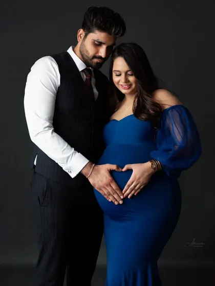 A symbol of love. The couple forms a heart with their hands on the baby bump, a simple and beautiful way to show their shared love for their coming child.
