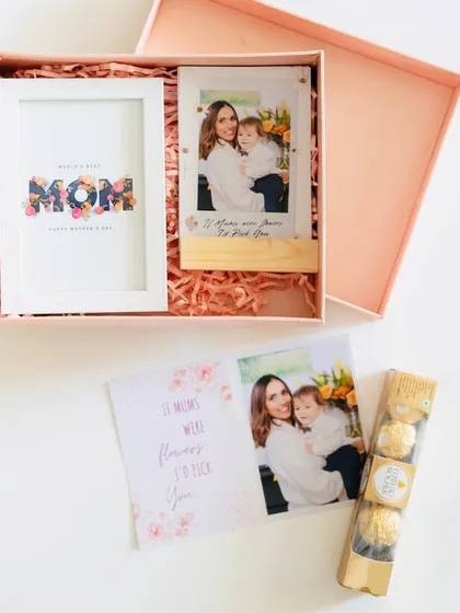 The Mother's Day hamper deconstructed to show its contents: a frame, a photo stand, and chocolates, with a matching card.