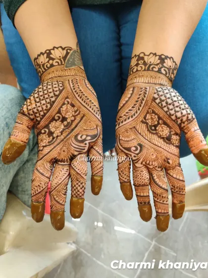 A classic mehendi design with a mix of floral and geometric patterns. The stained fingertips complete the traditional look.