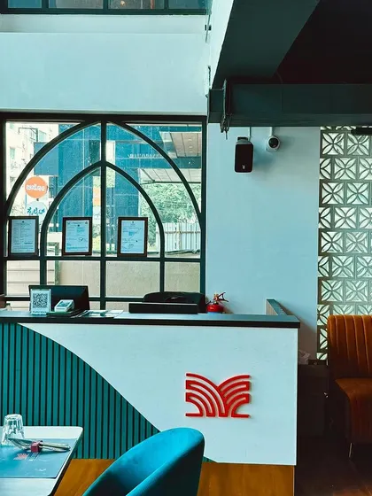 Our reception desk, featuring modern design with teal and white curves and our signature logo. This is where we welcome you to your fine dining experience.