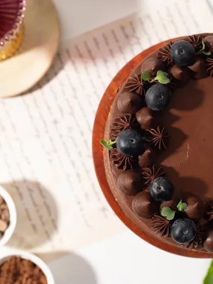 An overhead shot of our Chocolate and Berry Cake, highlighting the beautiful piping work and fresh blueberry and mint garnish.