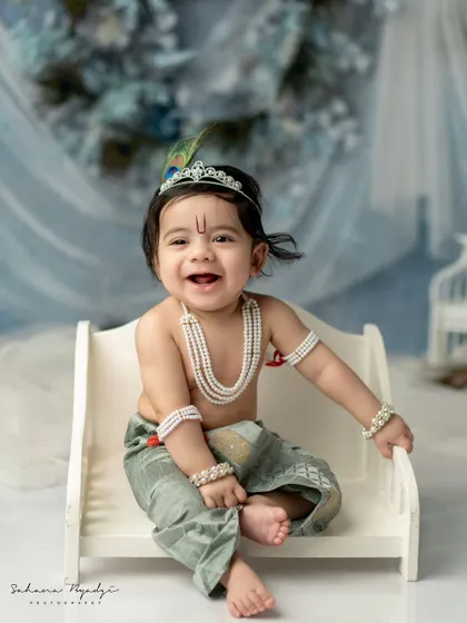 This little Krishna's blissful smile is everything. The simple, elegant setup with a cool blue and white theme provides a serene backdrop for his happy portrait.