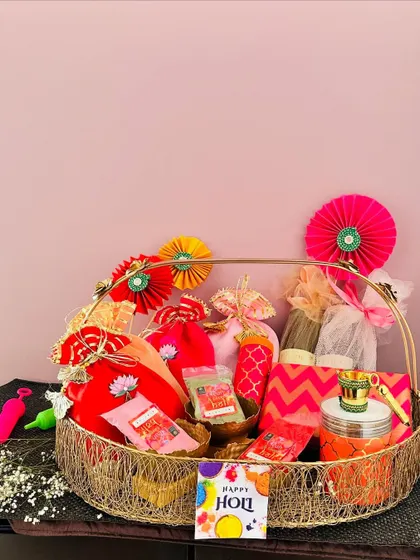 This large gold wire basket is perfect for a family-sized Holi hamper. It's packed with colorful potlis, a pichkari, thandai, and other treats for everyone to enjoy.