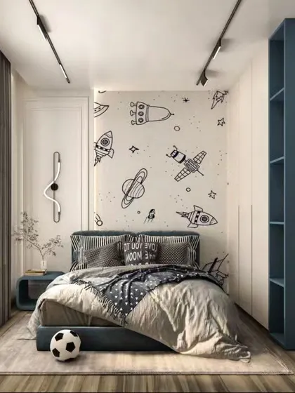A charming kid's bedroom with a space-themed wallpaper. The design is simple yet imaginative, with a cozy bed and a tall blue shelving unit for books and toys.