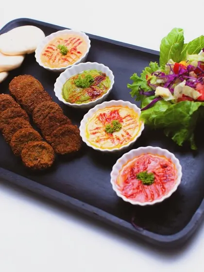 A clean and simple presentation of my Lebanese platter. This image clearly displays the key components: fresh pita bread, crispy falafel, a vibrant salad, and four different kinds of my homemade dips, ready to be enjoyed.