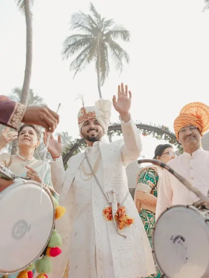 The groom's energetic arrival at the Baraat, surrounded by dhol players and celebrating family.
