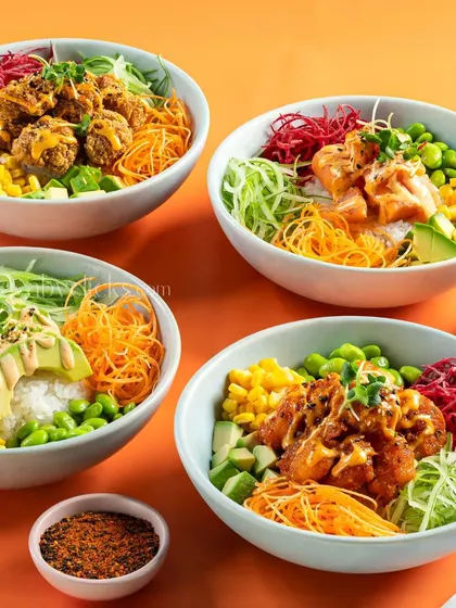 A collection of colorful poke bowls with various toppings like salmon, chicken, and avocado.
