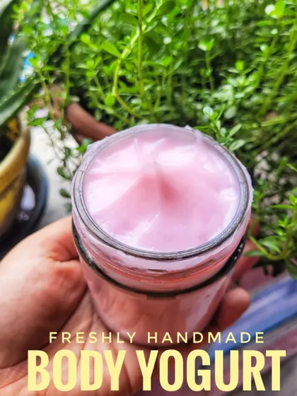 Holding a jar of my freshly made Cherry Blossom Body Yogurt. It has a lovely pink hue and a smooth texture that your skin will love.