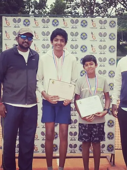 Two junior competitors from the AITA TS7 U-14 tournament pose with their awards alongside the tournament officials.