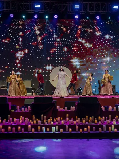 A wide shot of a performance during the 'Chandni Ratein' sangeet. The entire stage, from the candle-lined floor to the starry LED background, was designed to immerse everyone in the magical, moonlit theme.