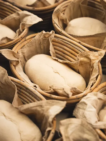 After shaping, the dough rests in banneton baskets. This proofing stage is crucial for developing the sourdough's complex flavor and signature open crumb.