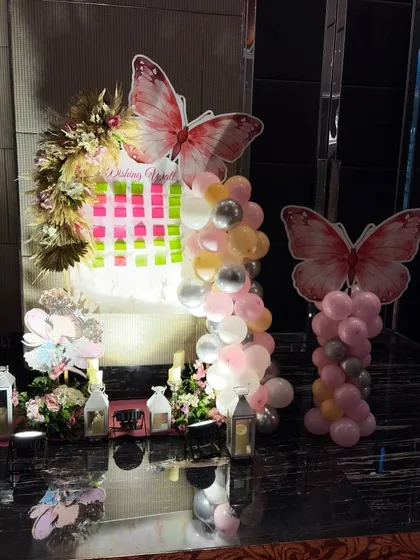 A whimsical butterfly-themed decoration for a child's birthday party. I used large butterfly cutouts, balloon columns in pastel colors, and a wishing board to create a magical and interactive party corner.