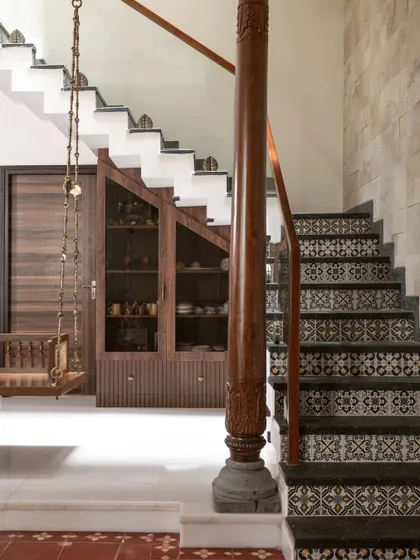 This view shows the clever use of space under the 'Varnika' staircase, where I integrated a crockery unit with glass doors. The traditional swing adds another layer of classic Indian design.