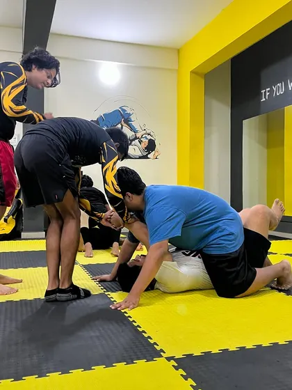 A coach guides students through a grappling technique. We provide hands-on instruction to ensure everyone understands the details.