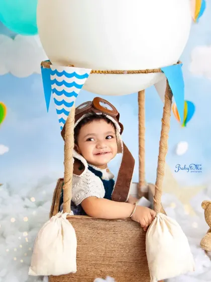 A joyful smile from high up in the sky. This travel-themed setup is perfect for celebrating the journey of your baby's first year.