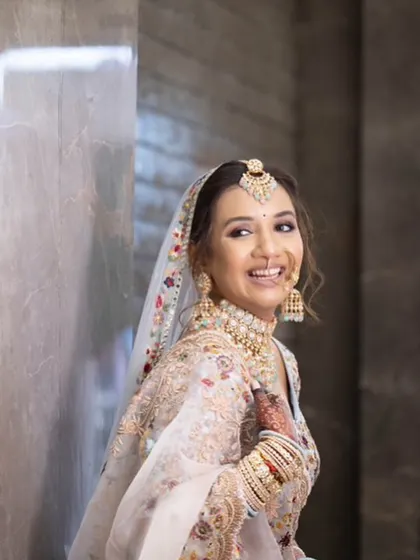 A candid, joyful shot of a bride in a beautiful pastel floral lehenga. The makeup is soft and romantic to match.