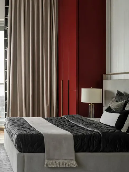 The deep maroon wardrobe in this master bedroom provides a bold pop of color. The clean lines and brass handles add a touch of modern luxury, complementing the room's sophisticated palette.