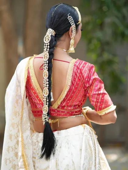 A view of the stunning back details, from the low-back blouse to the intricately decorated braid. Every element comes together to create a perfect bridal portrait.