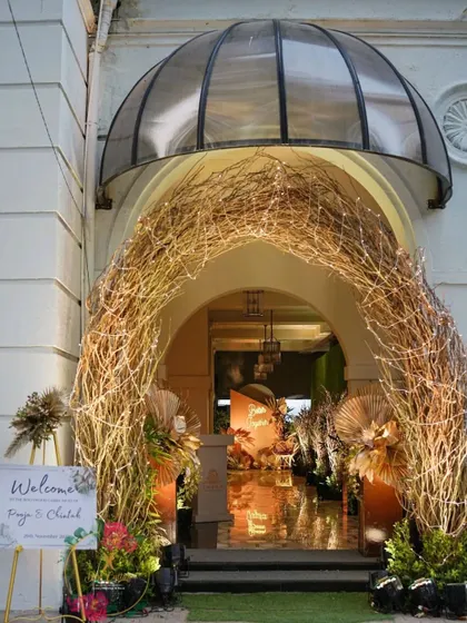 An enchanting rustic-chic entrance for a cocktail party. A twig archway wrapped in fairy lights leads guests into a warmly lit space, setting a magical tone for the evening.