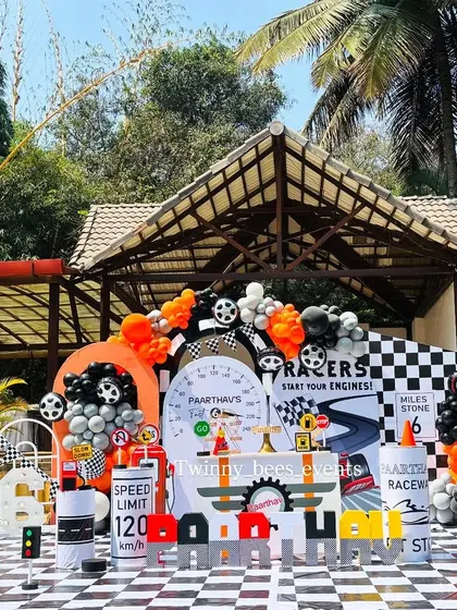 This is how we do a first birthday. We created a full-scale outdoor car racing theme, complete with a chequered floor, custom racetrack backdrop, and themed props like traffic cones and fuel barrels for Paarthav's big day.