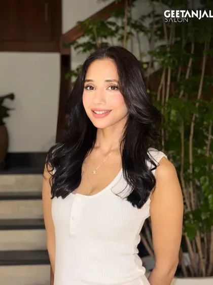 A classic black hair colour that looks striking and timeless, styled with soft, bouncy waves.