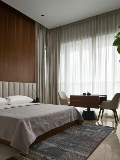 The Master Bedroom embodies quiet luxury with a natural walnut wood accent wall and a custom multifunctional study table. The space is designed to be spacious and immaculate, a true retreat for rest and creativity.