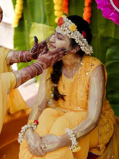A gentle moment during the Haldi application, showcasing the tradition and the bride's calm enjoyment.