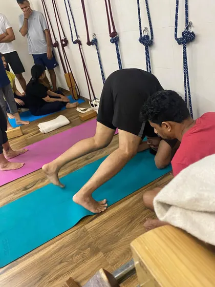 A student practicing Ardha Sirsasana (Half Headstand) on his forearms. This is a preparatory pose for the full headstand and builds shoulder strength.