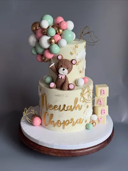 The full view of the two-tier cake for Neevah's naming ceremony. The pastel balloon cascade and teddy bear topper were designed to match the event's decor.