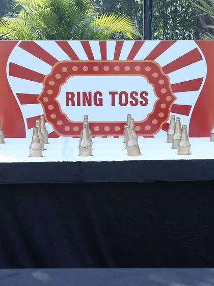 The classic ring toss game, set up with glass bottles and a professionally designed backdrop. It's a game of skill that always draws a crowd at carnival-themed events.