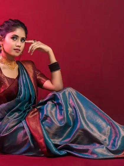 A seated portrait against a dramatic red background. This pose is elegant and shows off the beautiful colors of the saree.