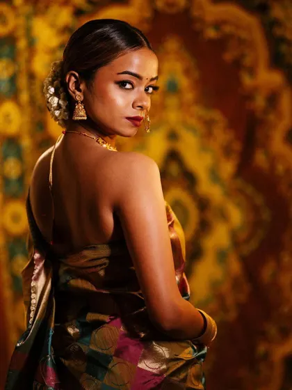 A stunning backless portrait in a traditional silk saree. The warm, golden lighting and rich background create a luxurious and sensual mood.