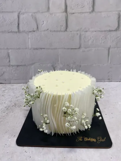 Another view of the minimalist white cake, showcasing the beautiful, subtle texture of the rice paper sails.